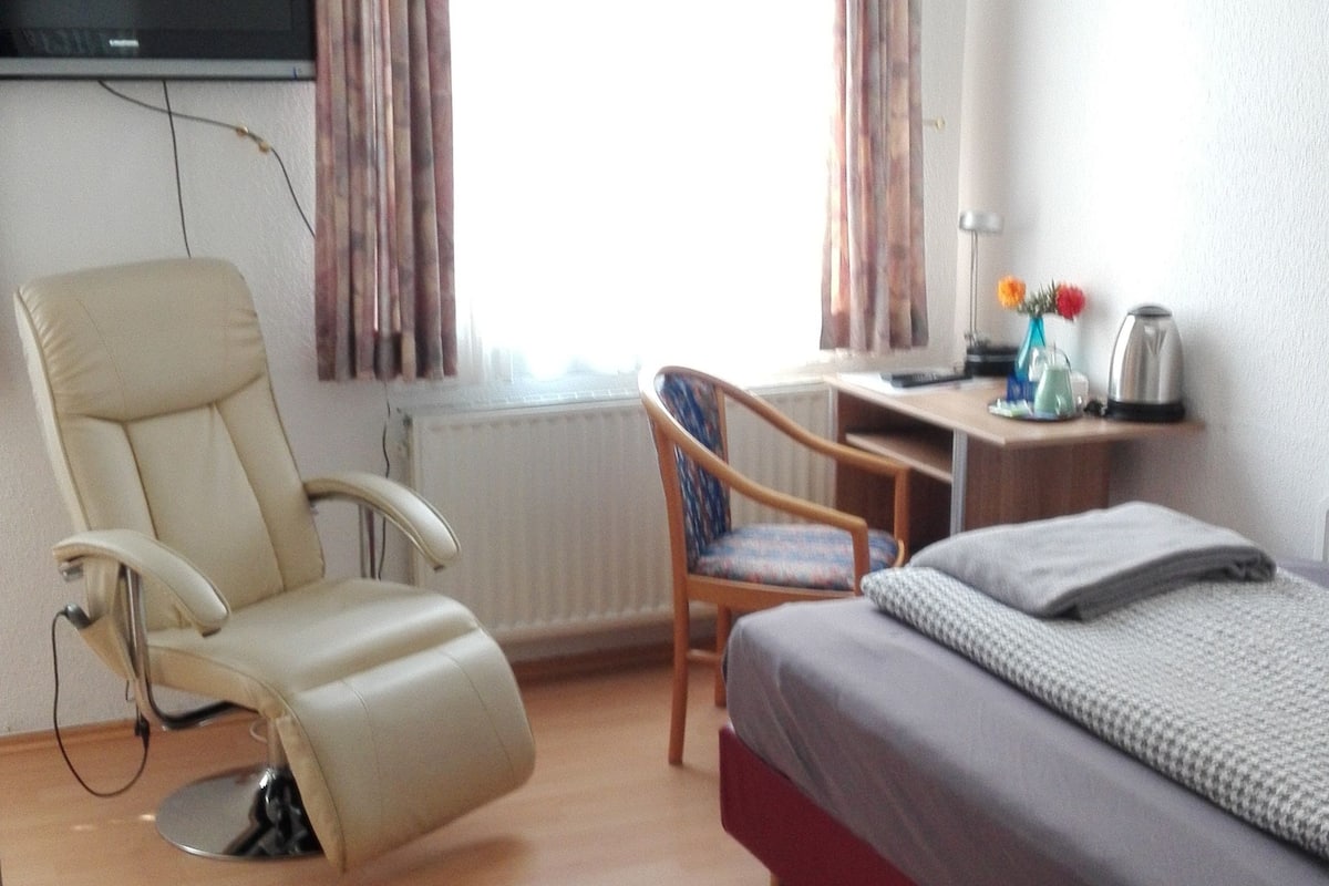 A hotel room with a bed, a desk, a chair, a television, and a window with curtains.