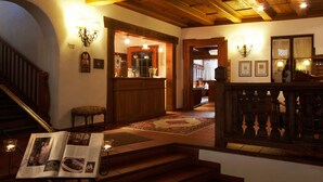 Un vestíbulo de hotel con una escalera de madera, un mostrador de recepción y un comedor.