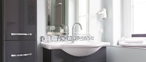 A modern bathroom with a white sink, dark cabinets, and a mirror.