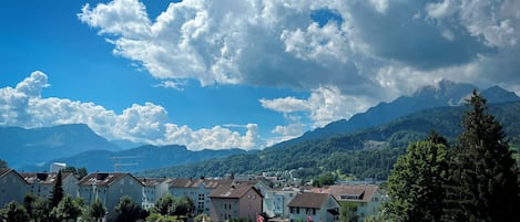 A residential area with houses, some with flags, and mountains in the background.