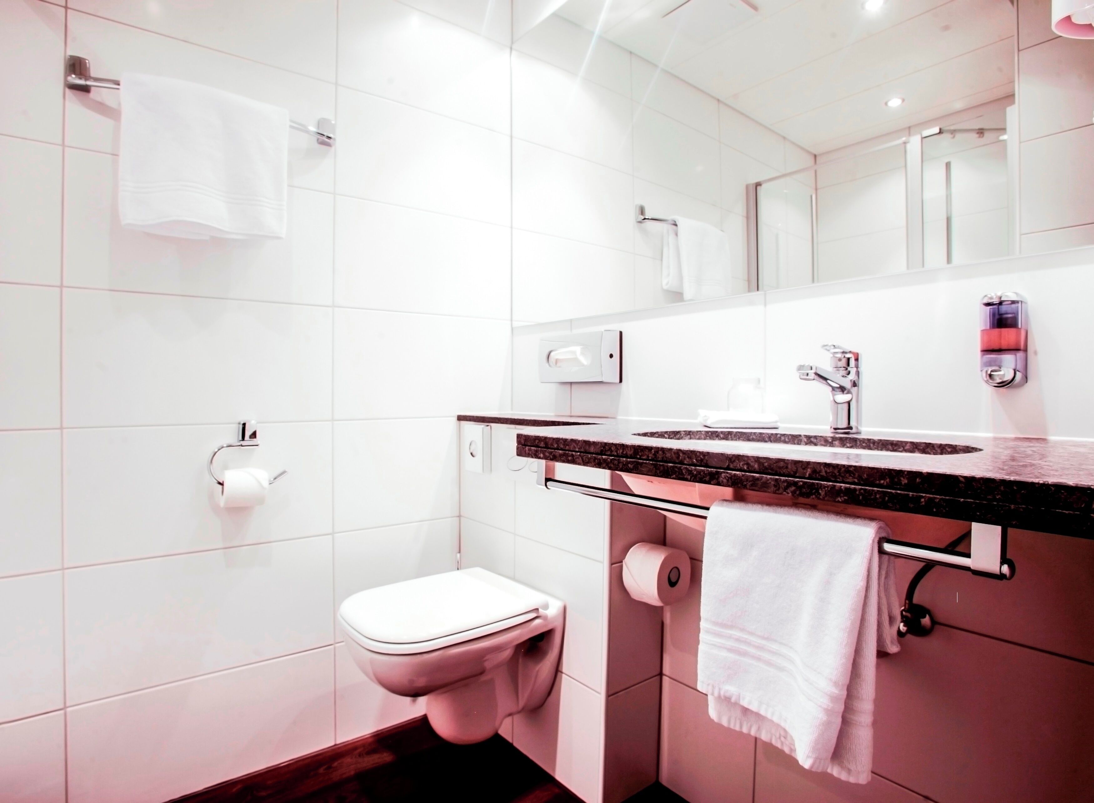Een moderne badkamer met toilet, wastafel en spiegel.