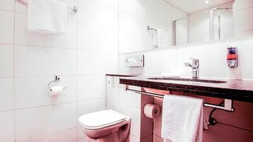 Een moderne badkamer met toilet, wastafel en spiegel.