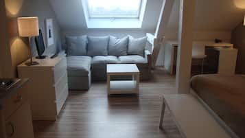 Un dormitori loft modern i compacte amb una finestra panoràmica, un sofà, una taula petita i un llit.