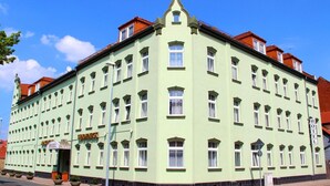 A light green building with multiple windows and a sign indicating it is a hotel. - Apartment Hotel Lindeneck (Erfurt)