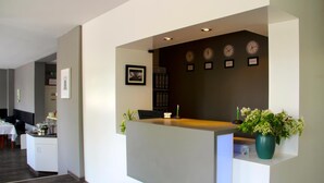 A reception area with a desk, a clock, a framed picture, and a potted plant. - Apartment Hotel Lindeneck (Erfurt)