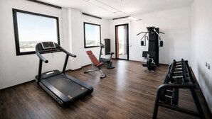 A modern gym with a treadmill, exercise bike, and weight machines. - Phi Hotel Milano (Baranzate)