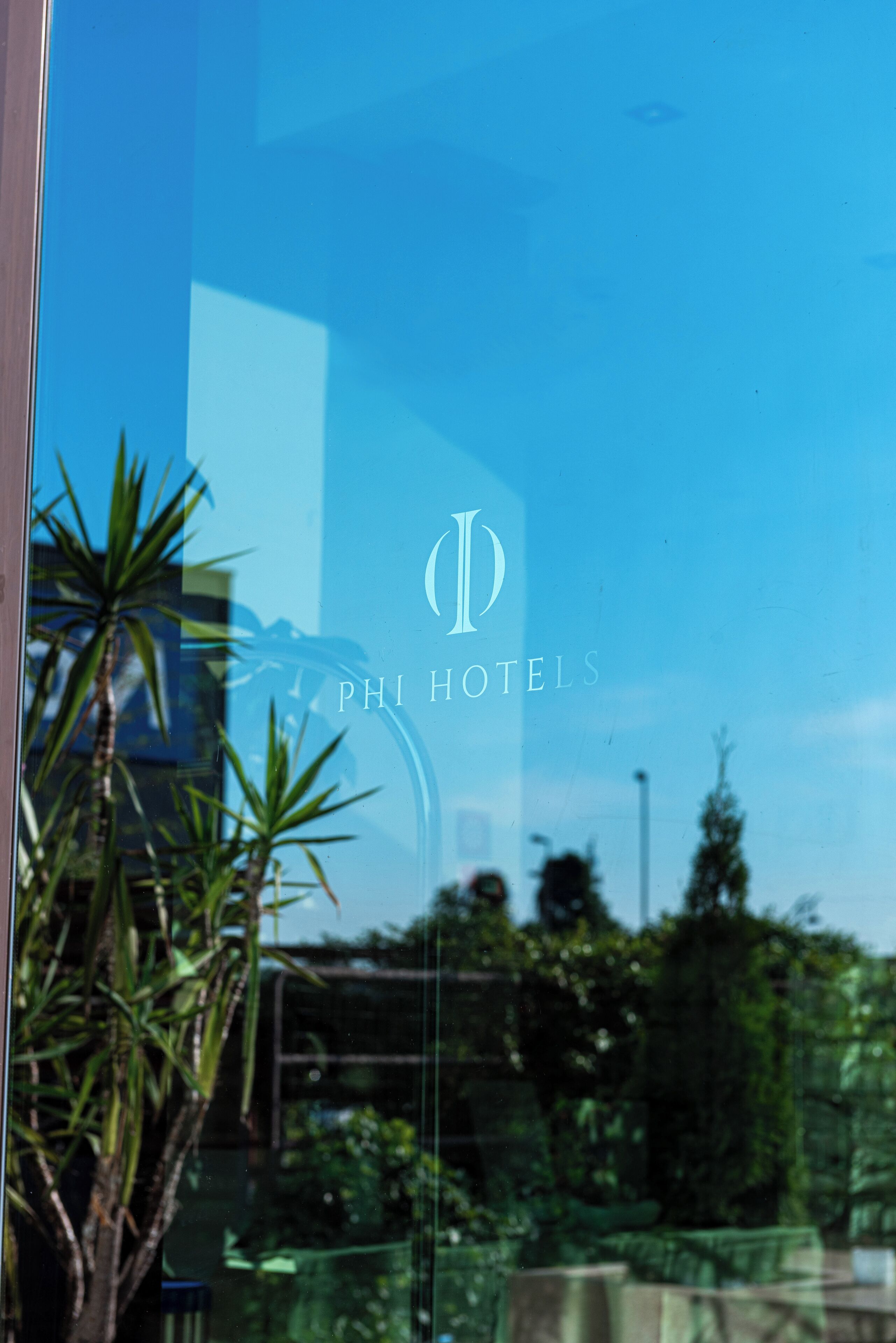 A glass window with the logo and name of PHI HOTELS reflected in it.