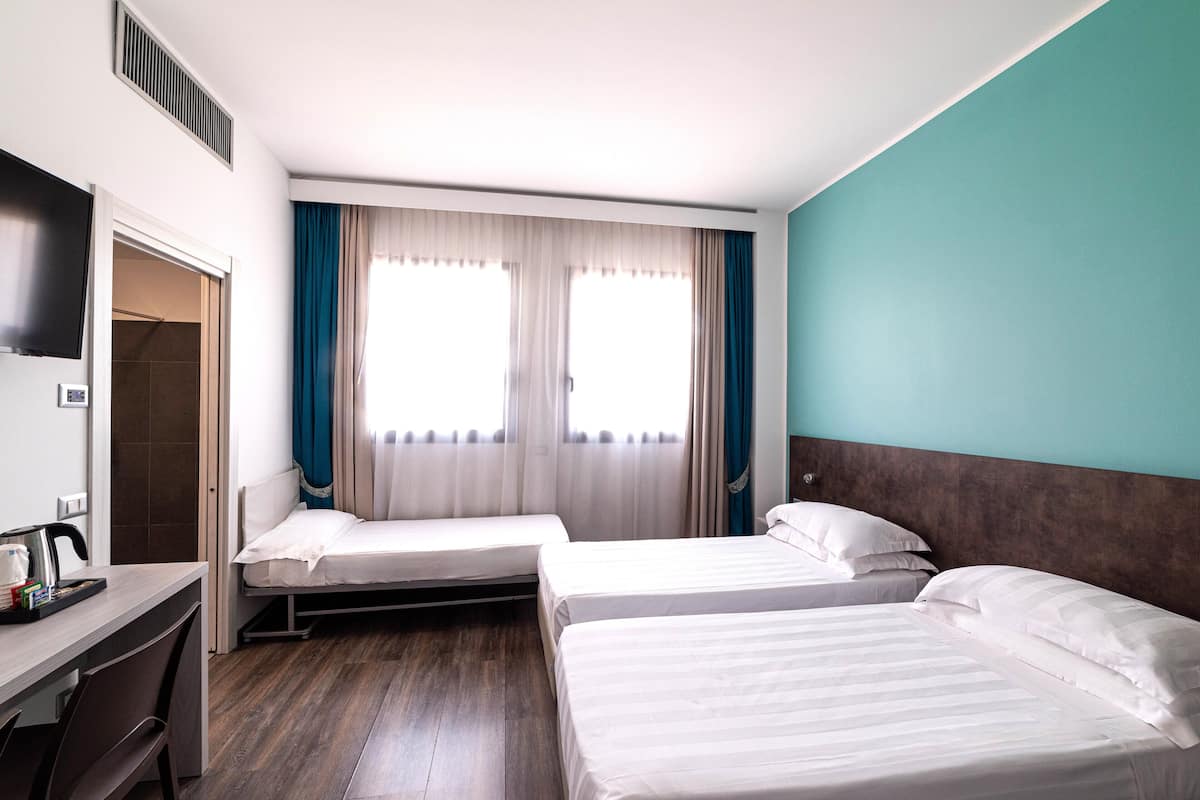 Une chambre d’hôtel avec deux lits, un bureau avec une machine à café et un espace douche.