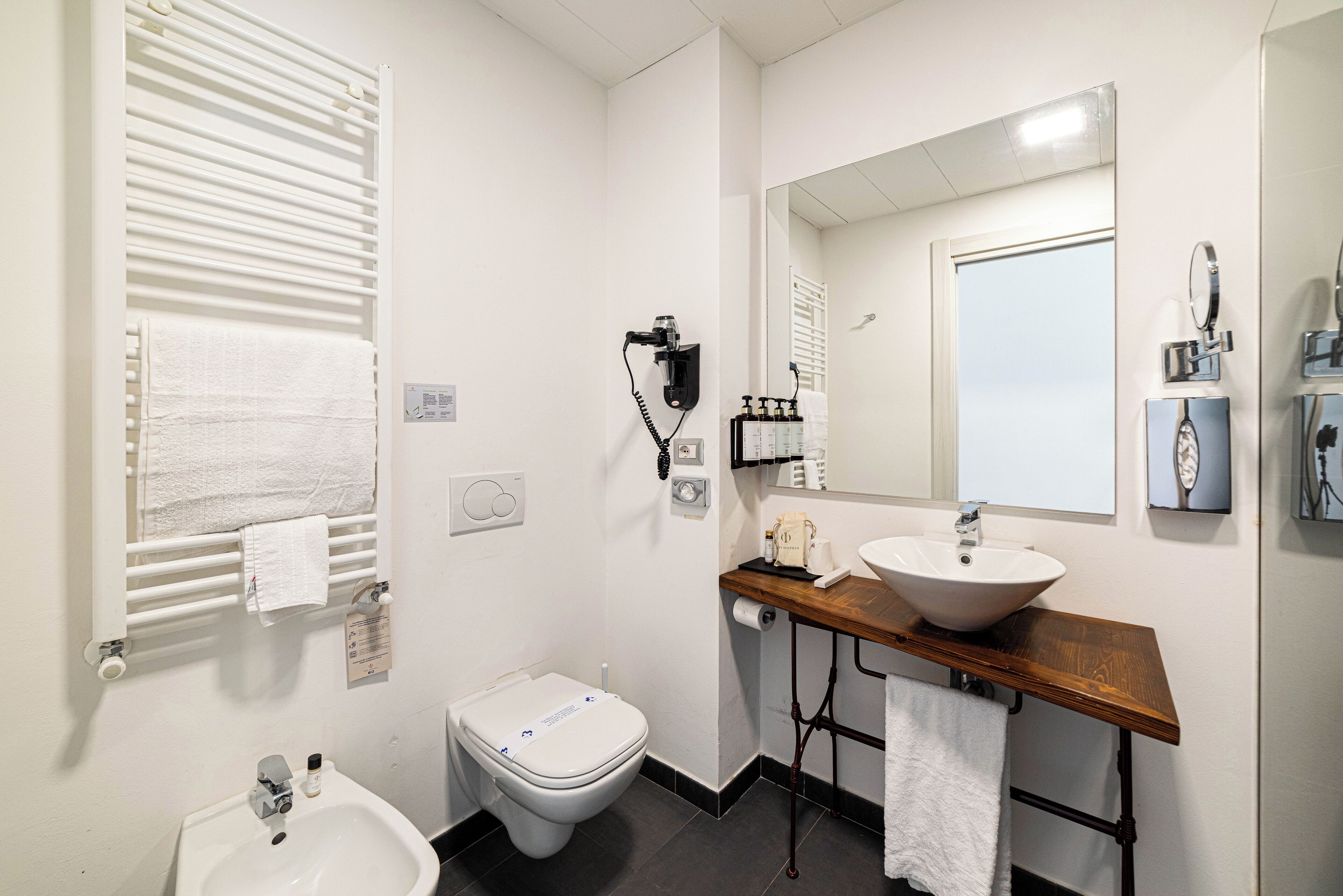 Une salle de bain avec un lavabo blanc, un miroir, un porte-serviettes et des toilettes.