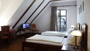 A bedroom with two beds, a desk with a computer, a chair, and a window with curtains. - Hotel Snorrenburg (Burbach)