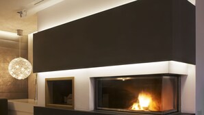 Una sala de estar moderna con chimenea empotrada, un candelabro redondo y piso de madera.