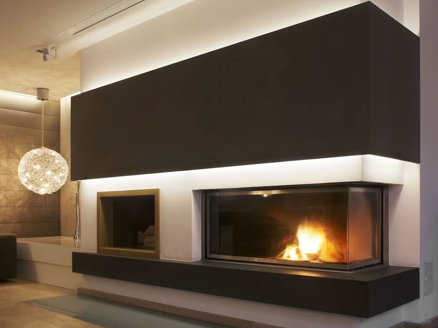 A modern living room with a built-in fireplace, a round chandelier, and a wooden floor.