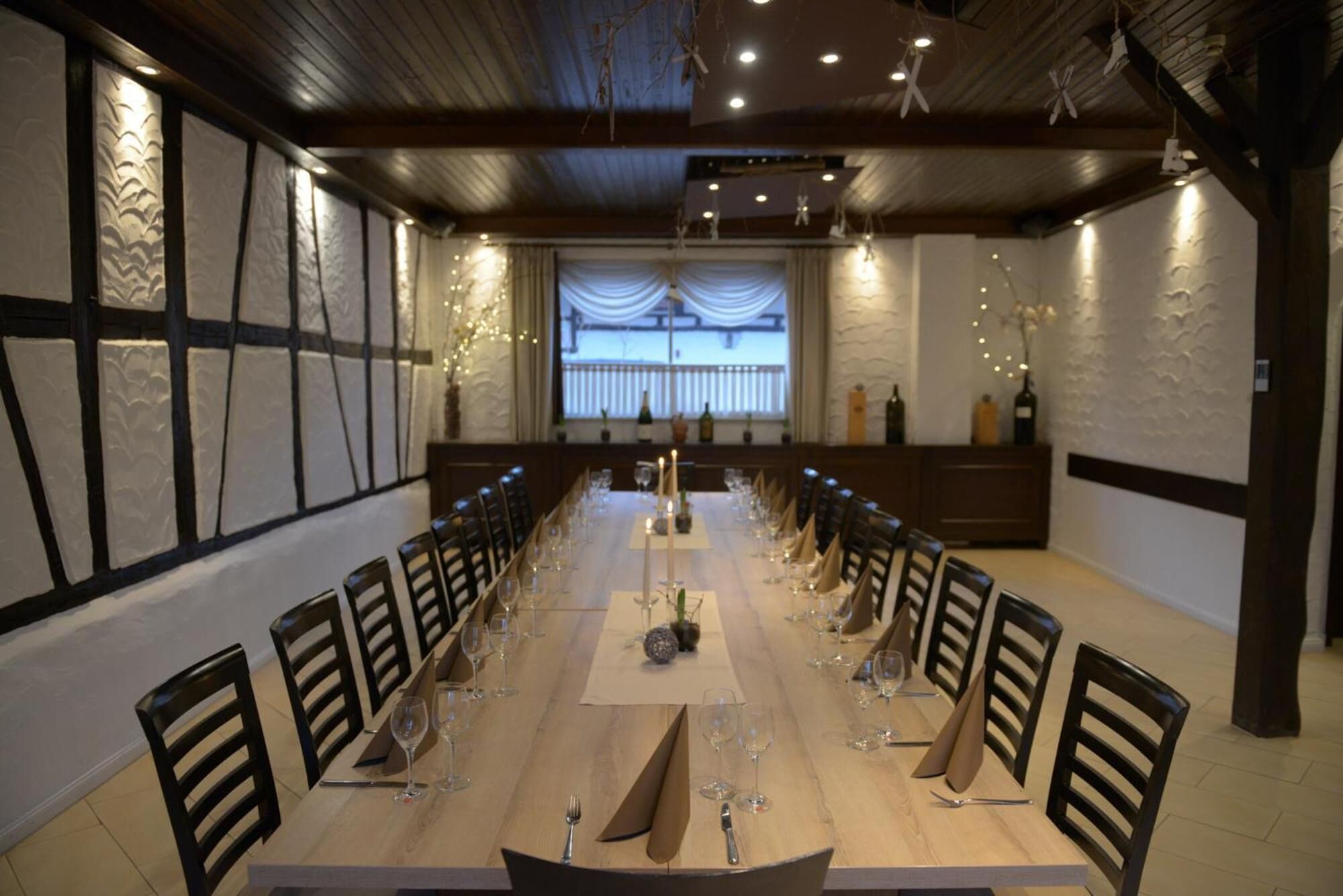 Una larga mesa de comedor con sillas, velas y copas de vino, ubicada en una habitación con vistas a un balcón.