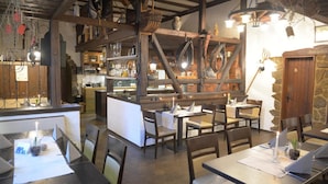 Un interior rústico con vigas de madera, una zona de bar y mesas preparadas para comer.