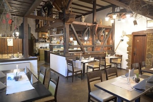 Un interior rústico con vigas de madera, una zona de bar y mesas preparadas para comer.