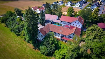 Vista aérea de un área residencial con varias casas, rodeada de vegetación y campos.