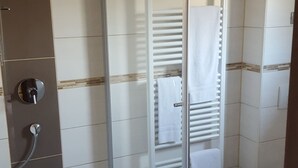 Un baño con cabina de ducha de vidrio, inodoro y lavabo con espejo.