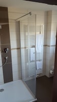 Un baño con cabina de ducha de vidrio, inodoro y lavabo con espejo.