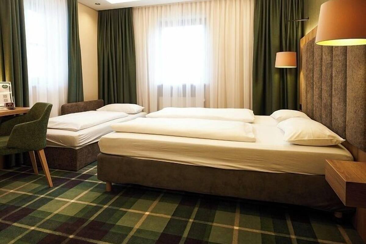 A hotel room with a bed, a desk, and a chair.
