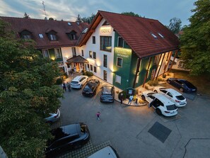 Un hotel con restaurante, varios autos estacionados y un sendero peatonal.
