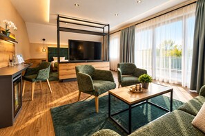 Una sala de estar moderna con sofá, sillones, una mesa de centro, televisor y vista al balcón.