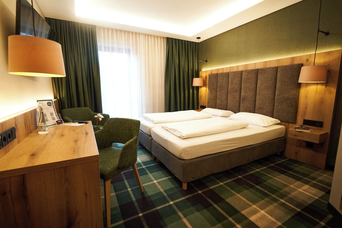 A hotel room with a bed, a desk, a chair, and a window with curtains.
