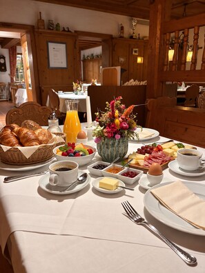 Un desayuno con croissants, fruta, queso y café.