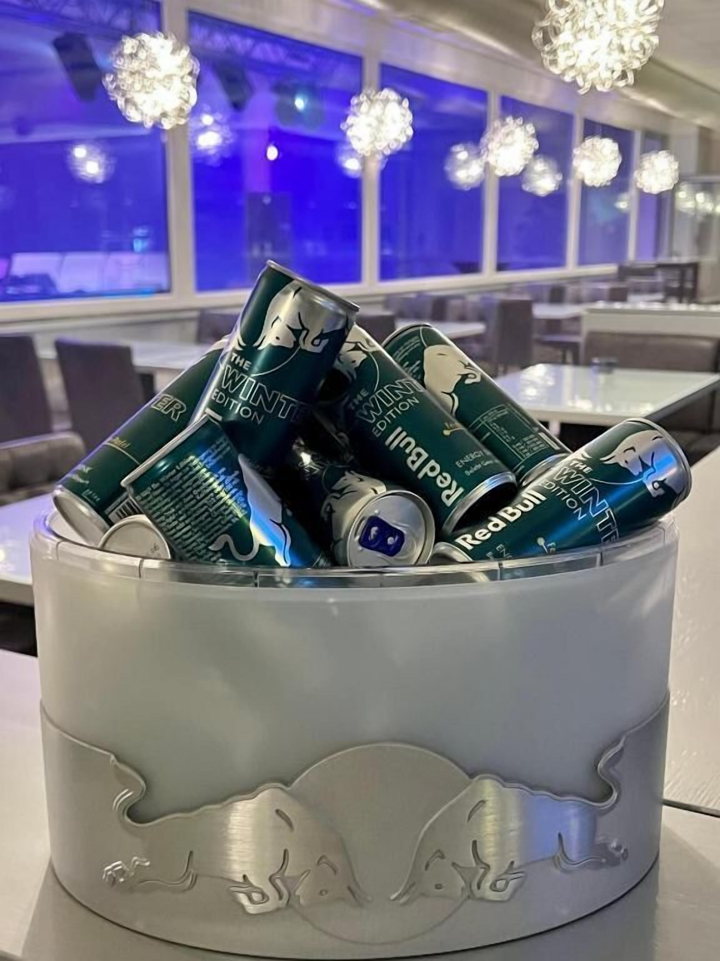Een metalen bak met reliëfdecoraties, gevuld met blikjes drank.