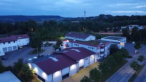 A multi-story building with a red roof, a sign for 'Sport Hotel,' and a parking lot. - Sporthotel Öhringen (Öhringen)