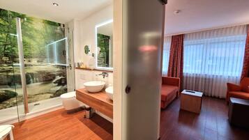 Un baño moderno con cabina de ducha de vidrio, tocador de madera y lavabo.