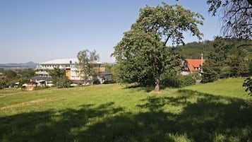 Een groot gebouw met meerdere verdiepingen en een plat dak, omgeven door gras en bomen.