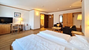 A hotel room with a bed, a desk with a television, a chair, and a small table. - Badhotel Restaurant Stauferland (Bad Boll)