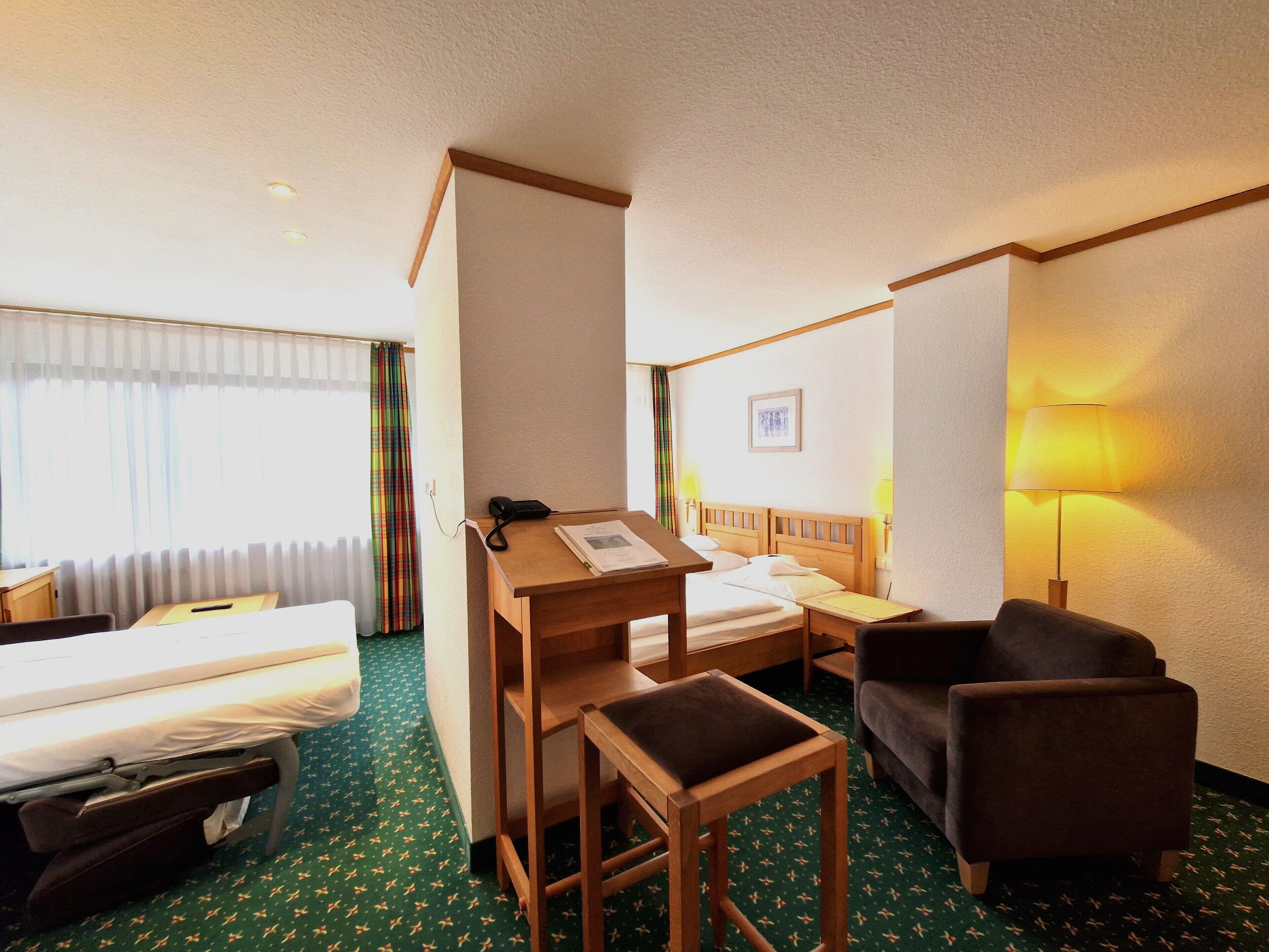 A hotel room with a bed, a desk, a chair, a small table, and a sofa.