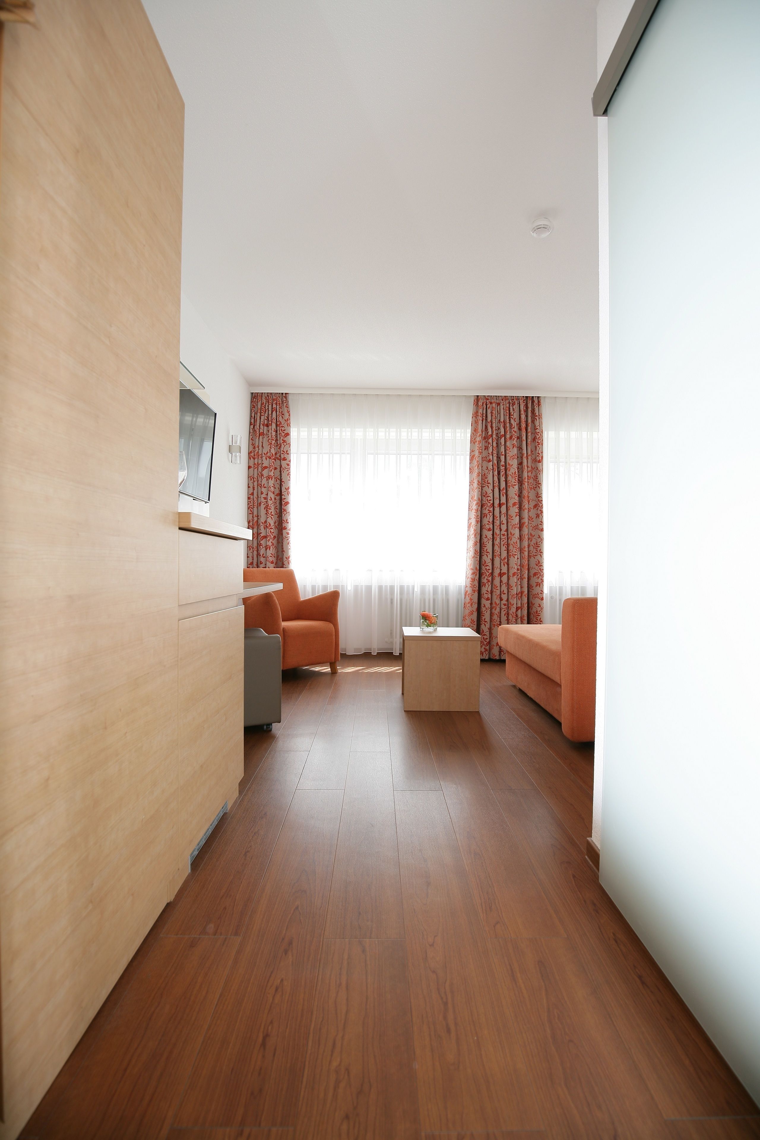 A modern living room with a wooden floor, a sofa, a coffee table, and a cabinet.