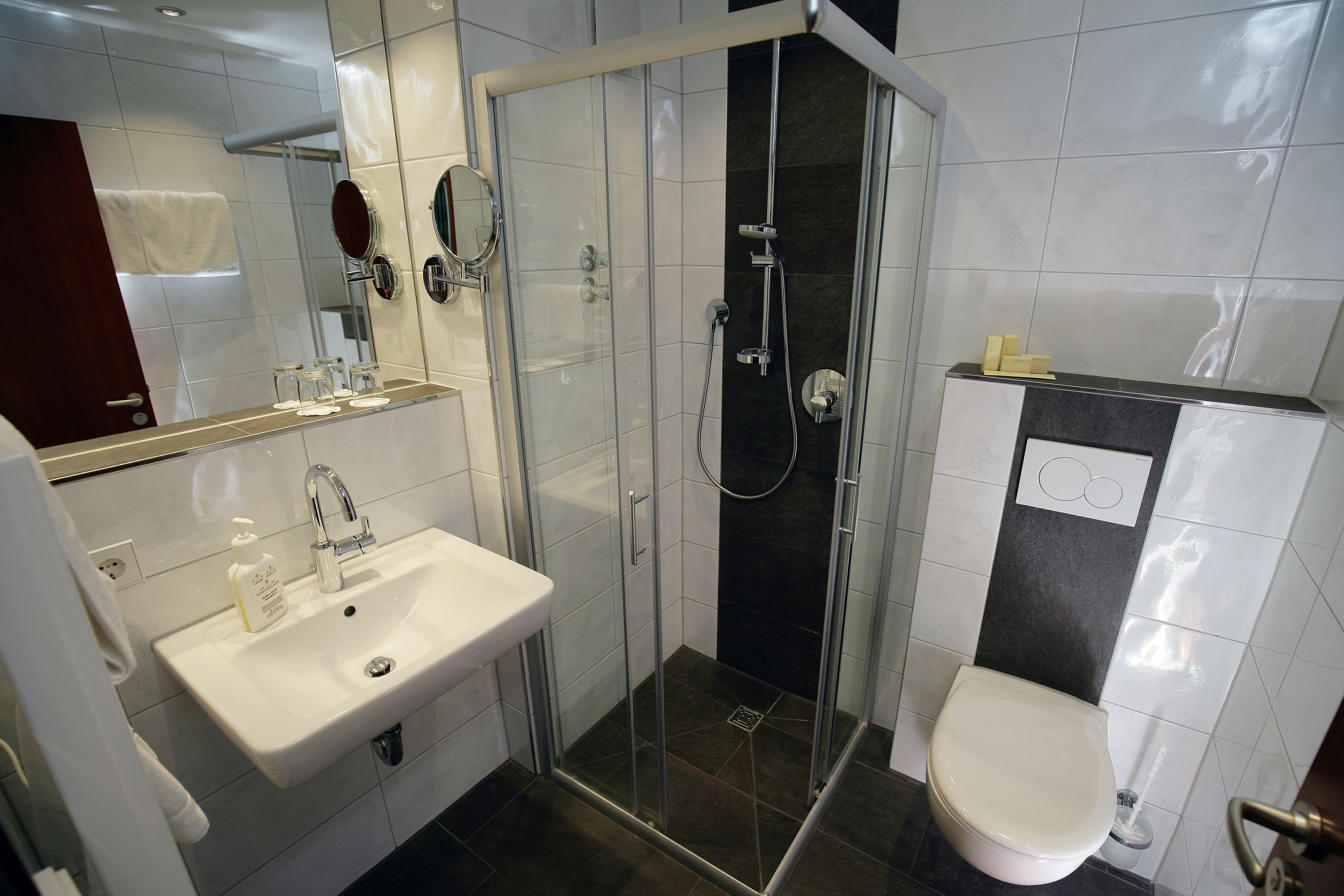 A modern bathroom with a glass-enclosed shower, a white sink, and a toilet.