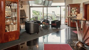 A modern lobby with a glass display case, leather seating, and a view of the outdoors. - Badhotel Restaurant Stauferland (Bad Boll)