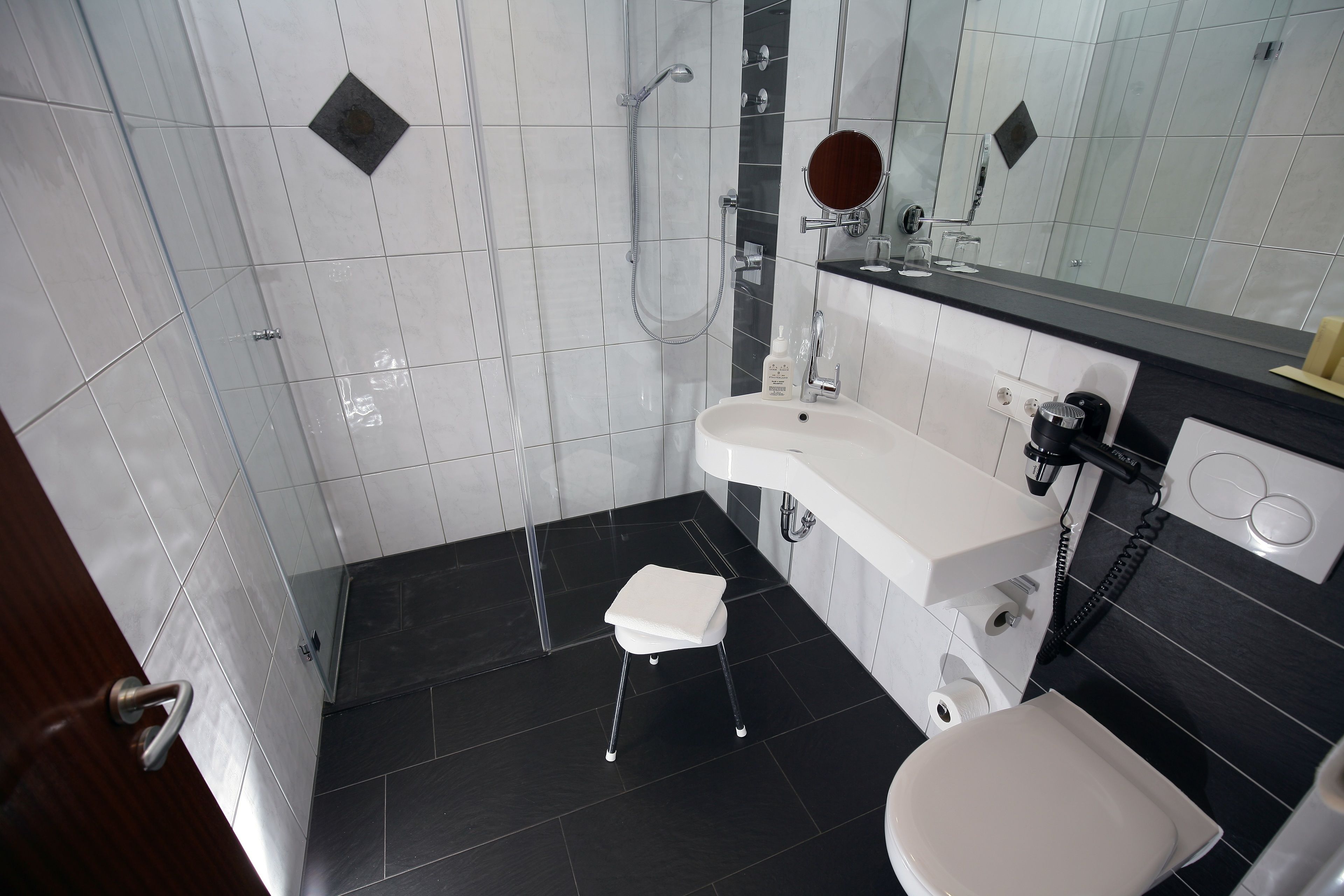 A modern bathroom with a shower, toilet, and sink.