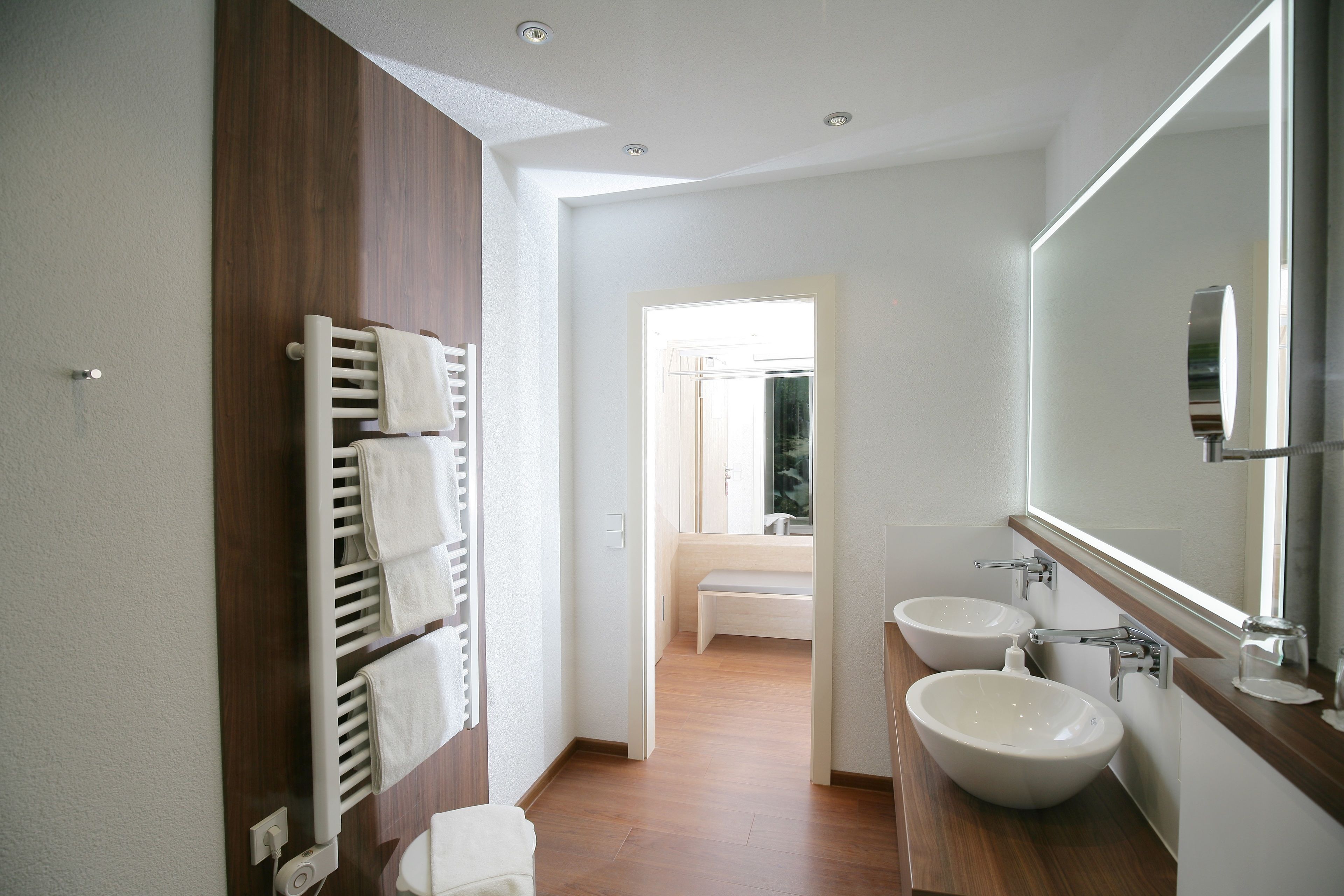 A modern bathroom with a wooden vanity, two sinks, and a large mirror.