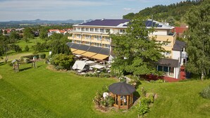Un hotel con varios pisos, un jardín en la azotea y un pequeño pabellón en el patio.