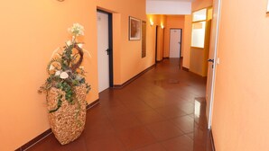 Un pasillo con paredes color naranja, una maceta tejida y puertas que dan a habitaciones.