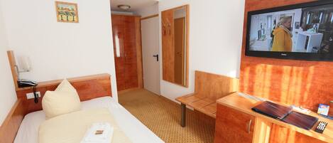 Una habitación de hotel con cama, escritorio, televisión y espejo.