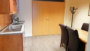 Una cocina compacta con pileta, cafetera y comedor con mesa y sillas.