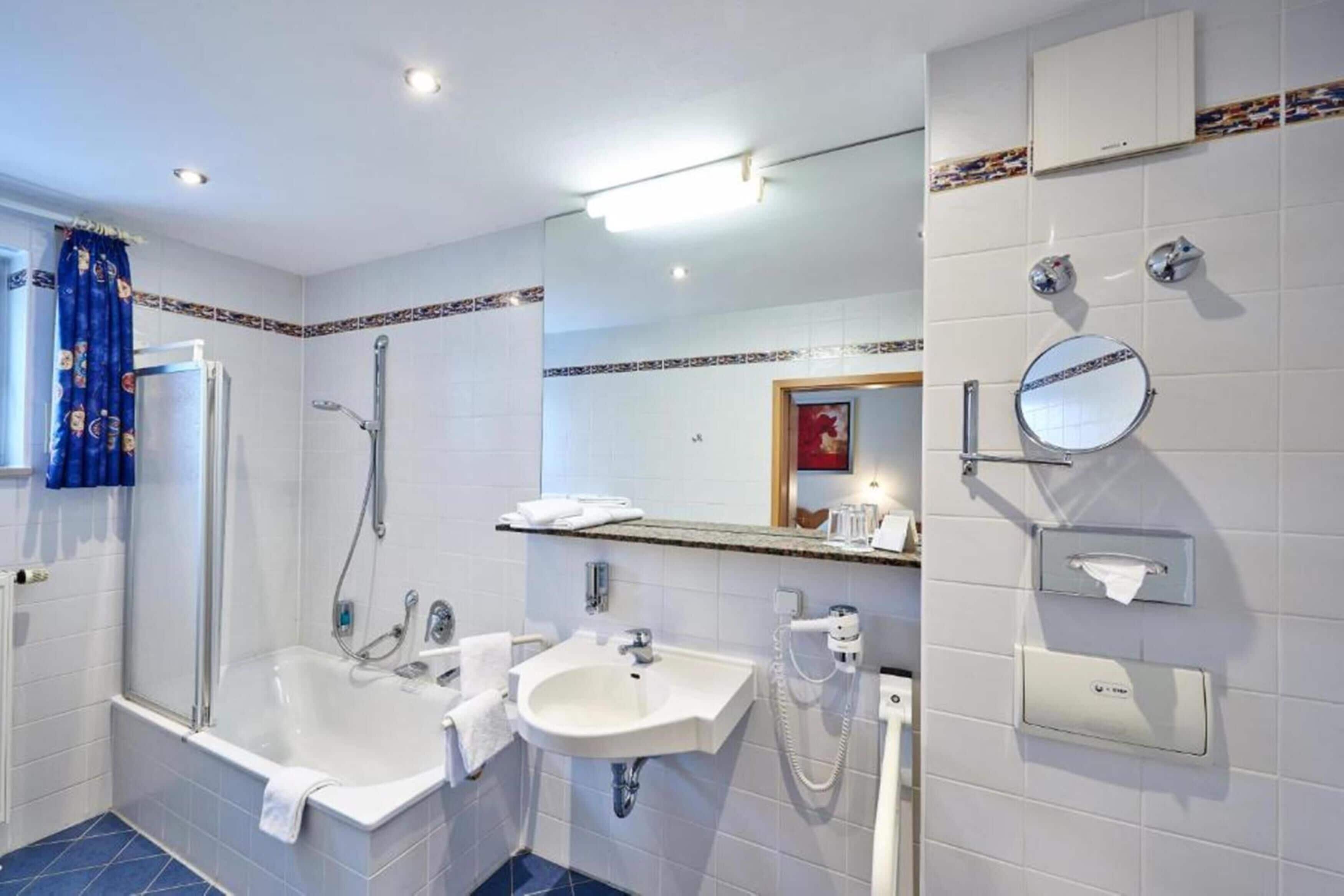 A modern bathroom with a bathtub, two sinks, a shower, and a large mirror.