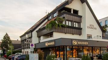 Ein Hotel namens 'Hotel Schumacher' mit modernem Design, inklusive eines Restaurants namens 'Wanner' im Erdgeschoss.