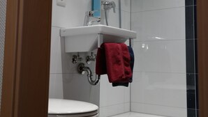 A modern bathroom with a white sink, toilet, and shower. - Motel 44 (Geseke)