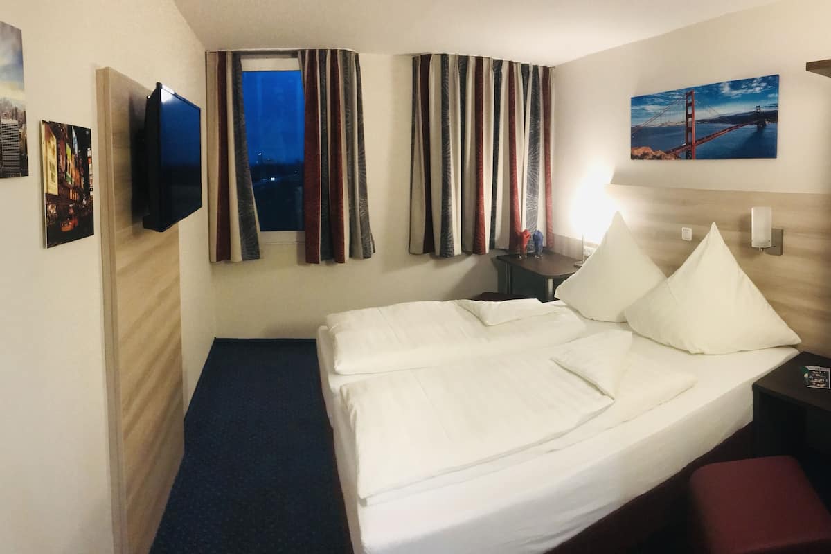 A hotel room with two beds, a TV, and artwork on the walls.