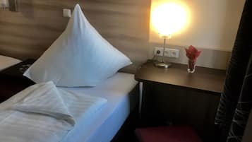 Ett hotellrum med en säng, ett nattduksbord med en lampa, en vas med blommor och en tavla som föreställer Route 66 på väggen.