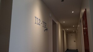 A hallway with numbers 112-117 on the wall, indicating room numbers. - Motel 44 (Geseke)