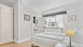 Une chambre à coucher avec un lit double, une table de chevet avec une lampe, une armoire et une fenêtre avec des rideaux.