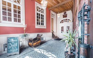 Um pátio de paralelepípedos com um edifício vermelho, uma porta branca e uma placa.